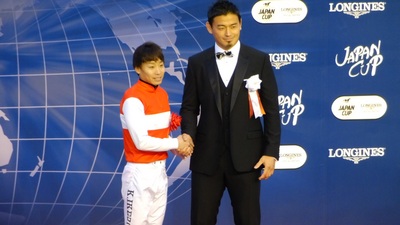 表彰式プレゼンターのラクビー日本代表・五郎丸歩選手と握手する池添謙一騎手